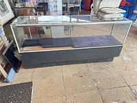 Full view of glass display case counter showing glass top and sides, black base