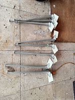 eight aluminum table legs laid out on floor