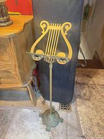 Front view of brass music stand showing lyre top, column and base