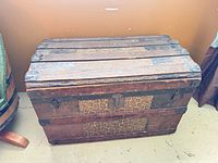 Front and top view of antique wooden trunk showing metal straps and decorative panels