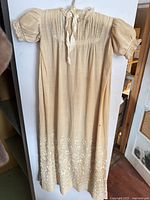 Front view of full gown showing pintucked bodice, sleeves, embroidered hem