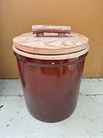 Front view of brown glazed stoneware crock with wooden lid and handle