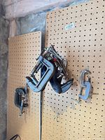 Group of various size C-clamps hanging on pegboard