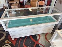 Front angled view of white glass display case counter