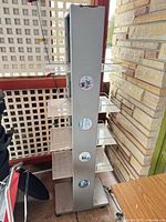 Full view of metal tower display rack with acrylic shelves and mirrored inserts