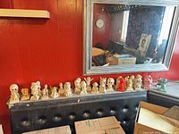 Row of sand cast figurines on bench under mirror
