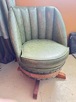 Front view of green vinyl barrel chair showing channel-tufted backrest and cushion