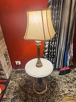 Full view of brass floor lamp with marble table and fabric shade