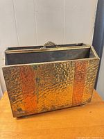 Front view showing hammered brass panels, handle, and feet