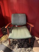 Front view of teak armchair with green upholstery