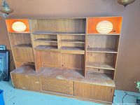 Full view of assembled teak wall unit showing base credenza, upper shelving sections, and overall wear