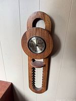Full view of wooden mid-century modern wall clock hanging on wall