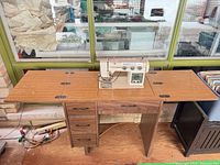 Full view of sewing cabinet with leaves extended and machine mounted