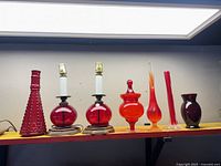 Seven red art glass items on shelf