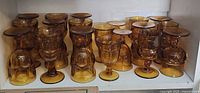 Full shelf view of amber glass goblets, some upright some inverted