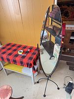 Full view of oval standing mirror beside table