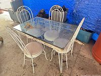 Full view of white metal patio table and four matching chairs