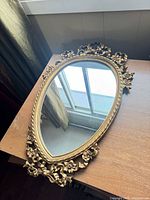 Front view of gold ornate oval mirror on table