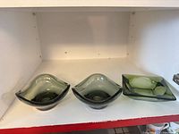 Three green art glass ashtrays displayed