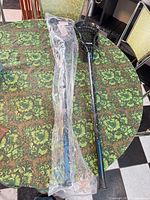 Two black youth lacrosse sticks on table, one wrapped