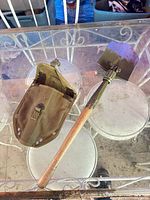 Full view of folded-out shovel with canvas sheath on glass table