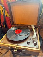Turntable open, record on platter, tonearm and controls visible