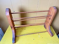 Front view of the wooden quilt rack showing three dowel rails, curved end panels, overall structure