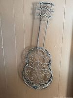 Full view of wrought iron guitar wall hanging on brown wall