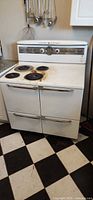 Full view of white GE electric range showing burners and oven doors