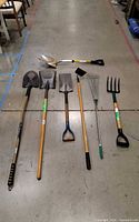 All six garden tools laid out—three shovels, hoe, rake, fork