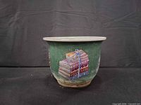 Front view of ceramic planter pot showing green glaze, cream rim and painted stack of books