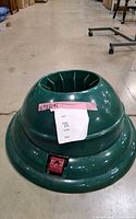 Full view of green plastic Christmas tree stand showing shape and red pedal