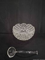 Cut glass serving bowl and ladle on black background
