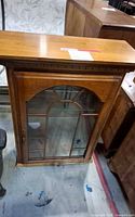 Front view of wood display cabinet with arched glass door
