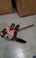 Chainsaw and hedge trimmer taped together on floor