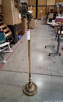 Full view of brass-tone floor lamp standing on warehouse floor