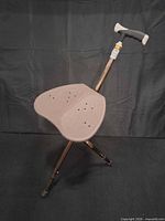 Cane in seated position showing seat shape, handle, and three legs