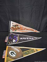 Three felt pennants showing Orioles, Ravens and Packers with retail header cards