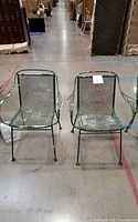 front view of two green metal mesh armchairs showing seat and back condition