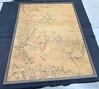 Full view of framed woven tapestry laying flat, showing design, frame, hanging cord