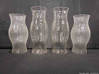 Front view of four clear glass hurricane candle shades