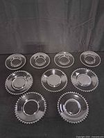 Top view of all nine clear glass plates arranged on black backdrop