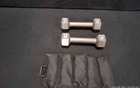 Two 5 lb hex dumbbells and one padded strap weight on black surface