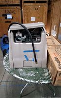 Front view of tan enclosed hose winder with hose and coupling visible