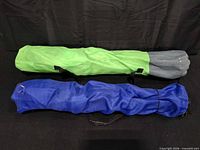 Two folded chairs in their carry bags, showing colors and straps