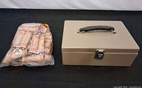 lock box closed next to plastic bag of quarter rolls