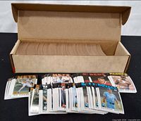 Full cardboard box of baseball cards with selection spread out in front