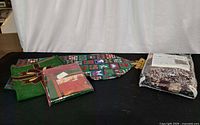 All four Sears holiday linens displayed: packaged tablecloth, packaged tree skirt, green poinsettia runner, patchwork runner with tassel