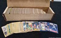 Open long box filled with vertically packed baseball cards; sample cards spread in front