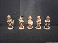 Front view of five M.I. Hummel ceramic child figurines arranged in a row